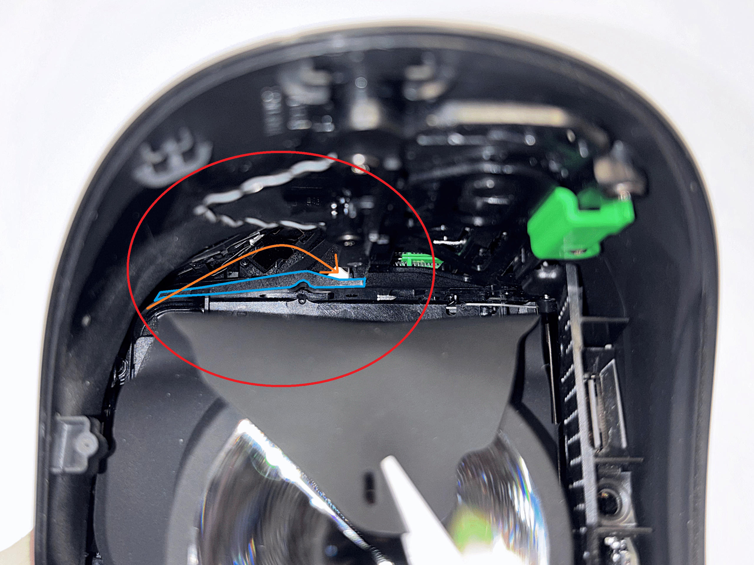 Plastic part marked in blue, with an orange arrow showing the cable path